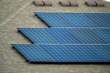 Standard american residential house with rooftop covered with solar photovoltaic panels for producing of clean electrical energy in suburban rural area. Concept of investment in autonomous home.