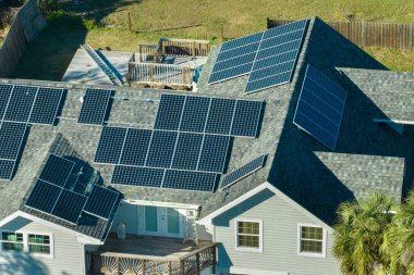 Kırsal kesimde temiz ekolojik elektrik enerjisi üretmek için çatısı güneş fotovoltaik panellerle kaplı bir Amerikan yerleşim evi. Özerk konut kavramı.