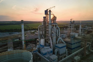 Yüksek fabrika yapısı olan çimento fabrikası ve endüstriyel üretim bölgesinde kule vinçleri var. Üretim, küresel sanayi ve hava kirliliği kavramı.