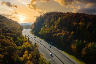 I-40 freeway road leading to Asheville in North Carolina thru Appalachian mountains with yellow fall forest and fast moving trucks and cars. Concept of high speed interstate transportation.