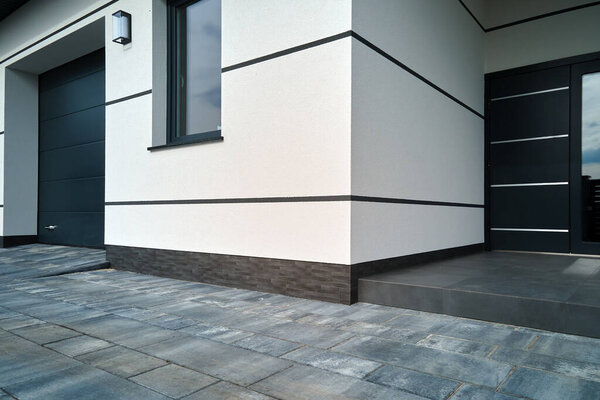 Exterior of modern contemporary comfortable house with front porch, stylish door, paved yard and shuttered windows.