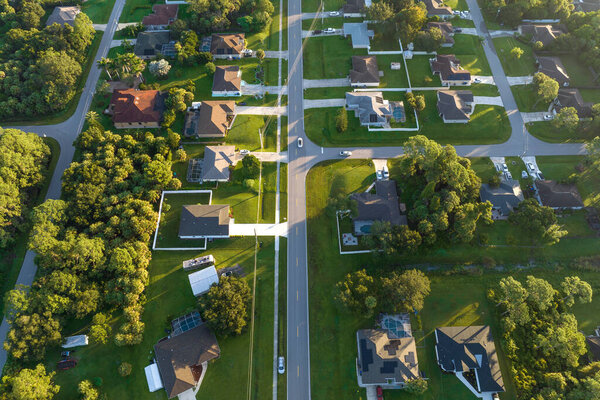 Aerial view of american small town in Florida with private homes between green palm trees and suburban streets in quiet residential area.