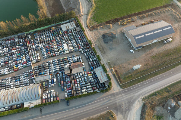 Aerial view of big parking lot of junkyard with rows of discarded broken cars. Recycling of old vehicles.
