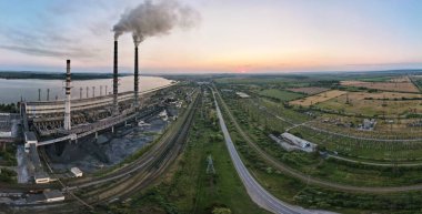 Kara dumanlı yüksek boruların hava görüntüsü gün batımında atmosferi kirletiyor. Fosil yakıt kavramına sahip elektrik enerjisi üretimi.