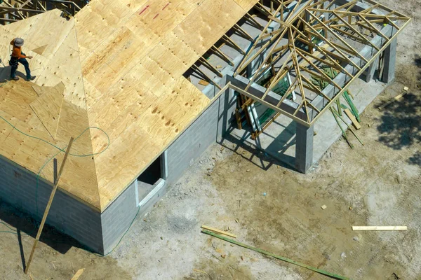 フロリダ州の農村部に木製のフレーム構造を持つ未完成の郊外の家の屋根の建設に取り組んでいるプロの建築家 アメリカにおける住宅開発の概念 — ストック写真