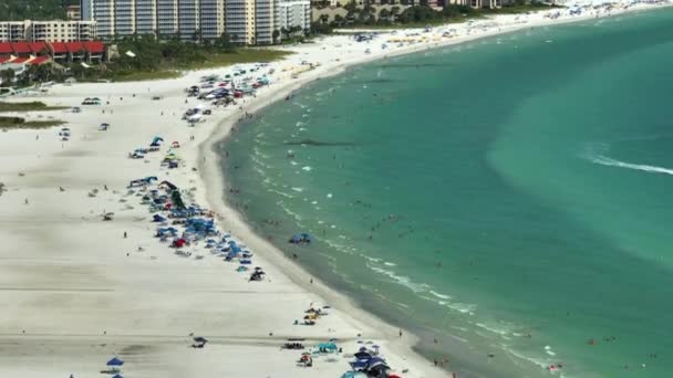 有名なシエスタキービーチの前にあるホテルの建物で 夏の晴れた日にアメリカのサラソータに柔らかい白い砂があります 暖かいフロリダ州で人気の休暇スポット — ストック動画