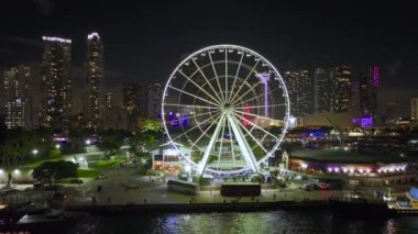 Biscayne Körfezi suları ve Brickell 'in yüksek aydınlatmalı gökdelenleri ve finans merkezleri ile birlikte Bayside Pazarı' ndaki Miami Gözlem Çarkı 'nın gece kentsel manzarası..