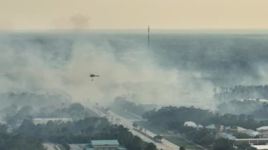Kuzey Liman Şehri, Florida 'da yangın söndüren itfaiye helikopteri. Acil servis helikopteri ormanda alevleri söndürmeye çalışıyor. Banliyö evlerinden yükselen yoğun duman.