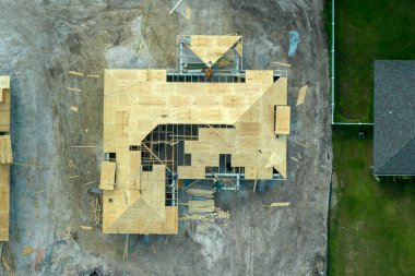 Florida 'nın banliyö bölgesinde ahşap iskeleti olan bitmemiş bir konutun çatı inşaatında çalışan inşaatçılar. Konut geliştirme kavramı.