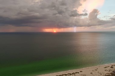 Şiddetli yağış mevsiminde fırtınalı gökyüzünde yaz akşamları kumlu deniz suyu üzerinde kara hava bulutları oluşuyor..