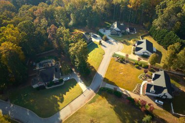 Güney Carolina 'nın banliyölerindeki sarı sonbahar ağaçları arasındaki pahalı konutların manzarası. Amerikan banliyölerinde emlak gelişimine örnek olarak Amerikan rüya evleri.