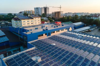 Sanayi binasının çatısına yeşil ekolojik elektrik üretmek için monte edilen mavi fotovoltaik güneş panellerinin hava görüntüsü. Sürdürülebilir enerji konsepti üretimi.