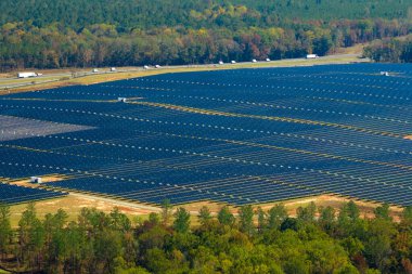 Temiz elektrik enerjisi üretmek için sıra sıra güneş fotovoltaik panelleri olan sürdürülebilir büyük elektrik santralinin havadan görünüşü. Sıfır emisyonlu yenilenebilir elektrik kavramı.