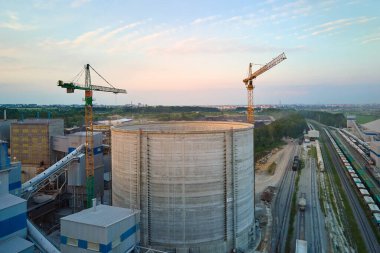 Yüksek fabrika yapısı olan çimento fabrikası ve endüstriyel üretim bölgesinde kule vinçleri var. Üretim ve küresel sanayi kavramı.