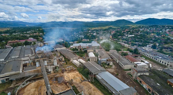 Aerial view of wood processing factory with smoke from production process polluting atmosphere at plant manufacturing yard.