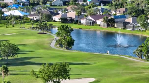 日当たりの良いフロリダ州のゴルフコースでゴルフカートを運転プロのゴルファー 裕福な人々の野外活動 — ストック動画