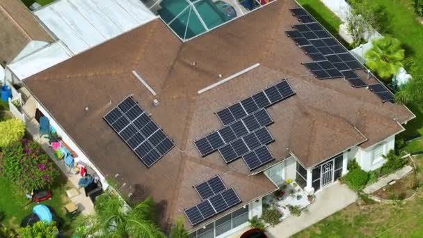 きれいな生態系の電気エネルギーを生成するための青い太陽光発電パネルと普通のアメリカの家庭の屋根の空中ビュー 排出ゼロをコンセプトとした再生可能エネルギー — ストック動画