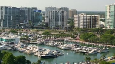 Sarasota Körfezi marinasının yukarıdan görünüşü birçok pahalı yat ve motorlu tekne içeriyor. Florida, ABD 'deki Sarasota şehrinin merkezindeki yüksek binalar. Ticari finans bölgesiyle Amerikan megapolis.