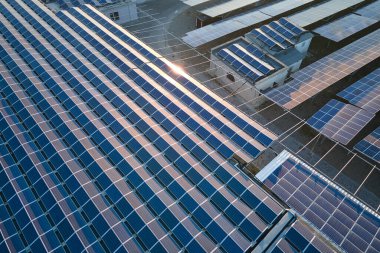 Sanayi binasının çatısına yeşil ekolojik elektrik üretmek için monte edilmiş mavi fotovoltaik panelli güneş enerjisi santralinin hava görüntüsü. Sürdürülebilir enerji konsepti üretimi.