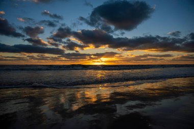 Ocean sunset landscape with soft evening sea water waves crushing on sandy beach.