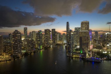 View from above of brightly illuminated high skyscraper buildings in downtown district of Miami Brickell in Florida, USA. American megapolis with business financial district at night. clipart