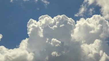 Beyaz kabarık kümülüs bulutlarının zamanı yaz mavi gökyüzünde şekilleniyor. Hareket eden ve değişen bulutlu hava durumu.
