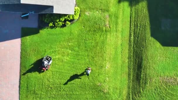 芝生芝刈り車で夏に草を刈る専門サービス労働者を刈る芝生のビュー 田舎の家の裏庭の風景 — ストック動画