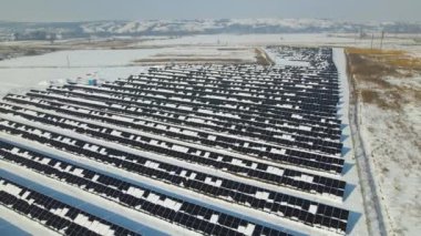 Aerial view of electrical power plant with solar panels covered with snow melting down in winter end for producing clean energy. Concept of low effectivity of renewable electricity in northern region.