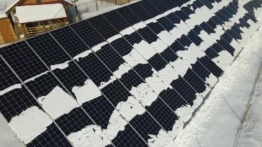 Aerial view of snow melting from covered solar photovoltaic panels at sustainable electric power plant for producing clean electrical energy. Low effectivity of renewable electricity in winter.
