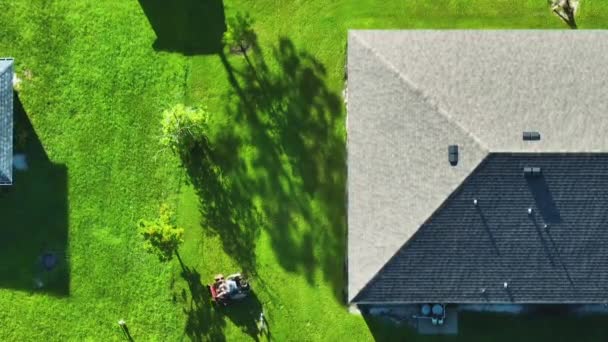 フロリダ郊外の自宅の裏庭に芝生の芝刈り機で夏に草を切断プロフェッショナルサービスワーカー — ストック動画
