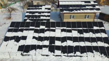 Aerial view of house roof with solar panels covered with snow melting down in winter end for producing clean energy. Concept of low effectivity of renewable electricity in northern region.