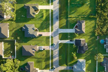 Aerial view of american small town in Florida with private homes between green palm trees and suburban streets in quiet residential area.