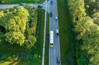 Amerikan sarı okul otobüsünün sabah erken saatlerde çocukları almak için banliyö sokağında araba sürüşünün hava görüntüsü. ABD 'de toplu taşıma.