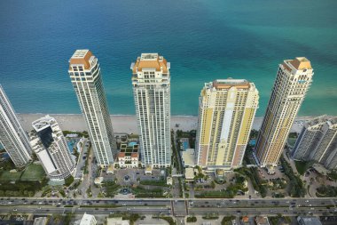 Sunny Isles Sahili 'nin havadan manzarası kalabalık sokak trafiği lüks oteller ve Atlantik Okyanusu kıyısındaki apartmanlar. Güney Florida 'daki Amerikan turizm altyapısı.