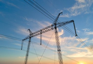 Gün batımında elektrik hatları olan yüksek voltaj kulesi. Elektrik aktarımı.