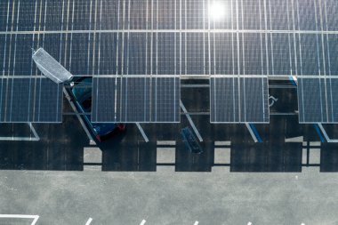 Park alanının gölgesinde, temiz enerjinin etkin üretimi için park etmiş arabaların güneş panellerine rüzgar hasarı.