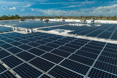 Sanayi binasının çatısına yeşil ekolojik elektrik üretmek için monte edilen mavi fotovoltaik güneş panellerinin hava görüntüsü. Sürdürülebilir enerji konsepti üretimi.