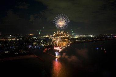 Aerial view of bright fireworks exploding with colorful lights over sea shore on US Independence day holiday.