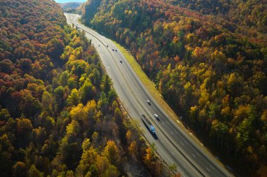 Aerial view of I-40 freeway in North Carolina leading to Asheville through Appalachian mountains in golden fall with fast moving trucks and cars. Interstate transportation concept.