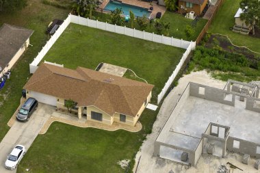 Tamamlanmamış, beton duvarlı, inşaat halindeki ahşap çatı kirişleri monte etmeye hazır özel evin havadan görüntüsü..