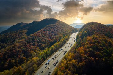 I-40 freeway in North Carolina leading to Asheville through Appalachian mountains in golden fall with fast moving trucks and cars. Interstate transportation concept.