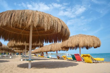 Straw shade umbrella in sea tropical region against blue vibrant sky in summer.