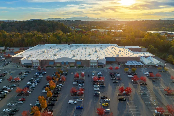 stock image Aerial view of large parking lot in front of rgocery store with many parked colorful cars. Carpark at supercenter shopping mall with lines and markings for vehicle places and directions.