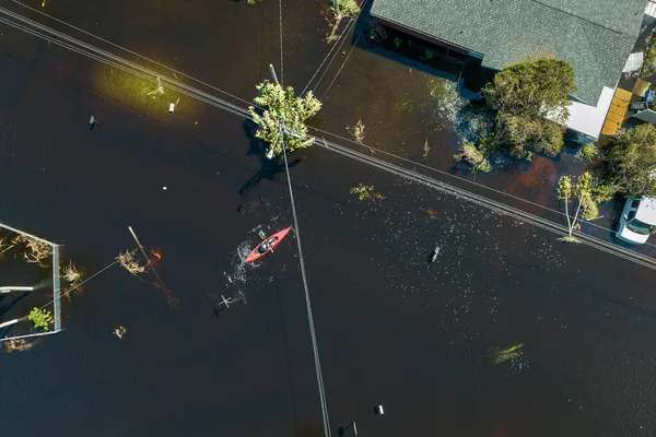 自然災害の結果 ハリケーンイアンに囲まれた浸水した通りに浮かぶカヤックボートフロリダ州の住宅街の洪水の水の家 — ストック写真