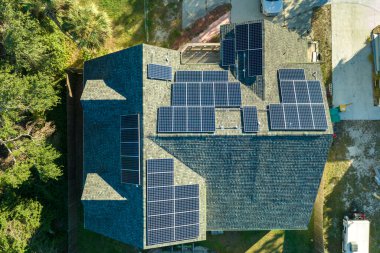 Kırsal kesimde temiz ekolojik elektrik enerjisi üretmek için çatısı güneş fotovoltaik panellerle kaplı bir Amerikan yerleşim evi. Özerk konut kavramı.