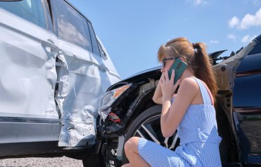 Üzgün kadın sürücü cadde tarafında cep telefonuyla konuşuyor. Araba kazasından sonra acil servisi arıyor. Yol güvenliği ve sigorta kavramı.