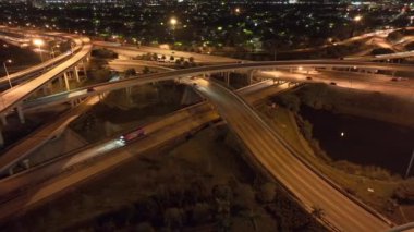 Miami, Florida 'da gece Amerikan otoyolu kavşağında hızlı giden araba ve kamyonlarla hava görüntüsü. ABD ulaşım altyapısının üstünden görüntüle.