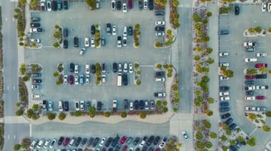 Birçok renkli arabanın park ettiği büyük otoparkın havadan görüntüsü. Florida, Sarasota 'daki Siesta Key plajının önündeki otoparkta araç yerleri ve yönleri için çizgiler ve işaretler var..