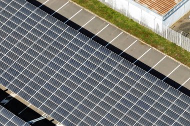 Sanayi binasının çatısına yeşil ekolojik elektrik üretmek için monte edilen mavi fotovoltaik güneş panellerinin hava görüntüsü. Sürdürülebilir enerji konsepti üretimi.