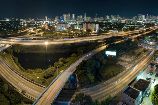 Above view of wide highway crossroads in Miami, Florida at night with fast driving cars. USA transportation infrastructure concept.